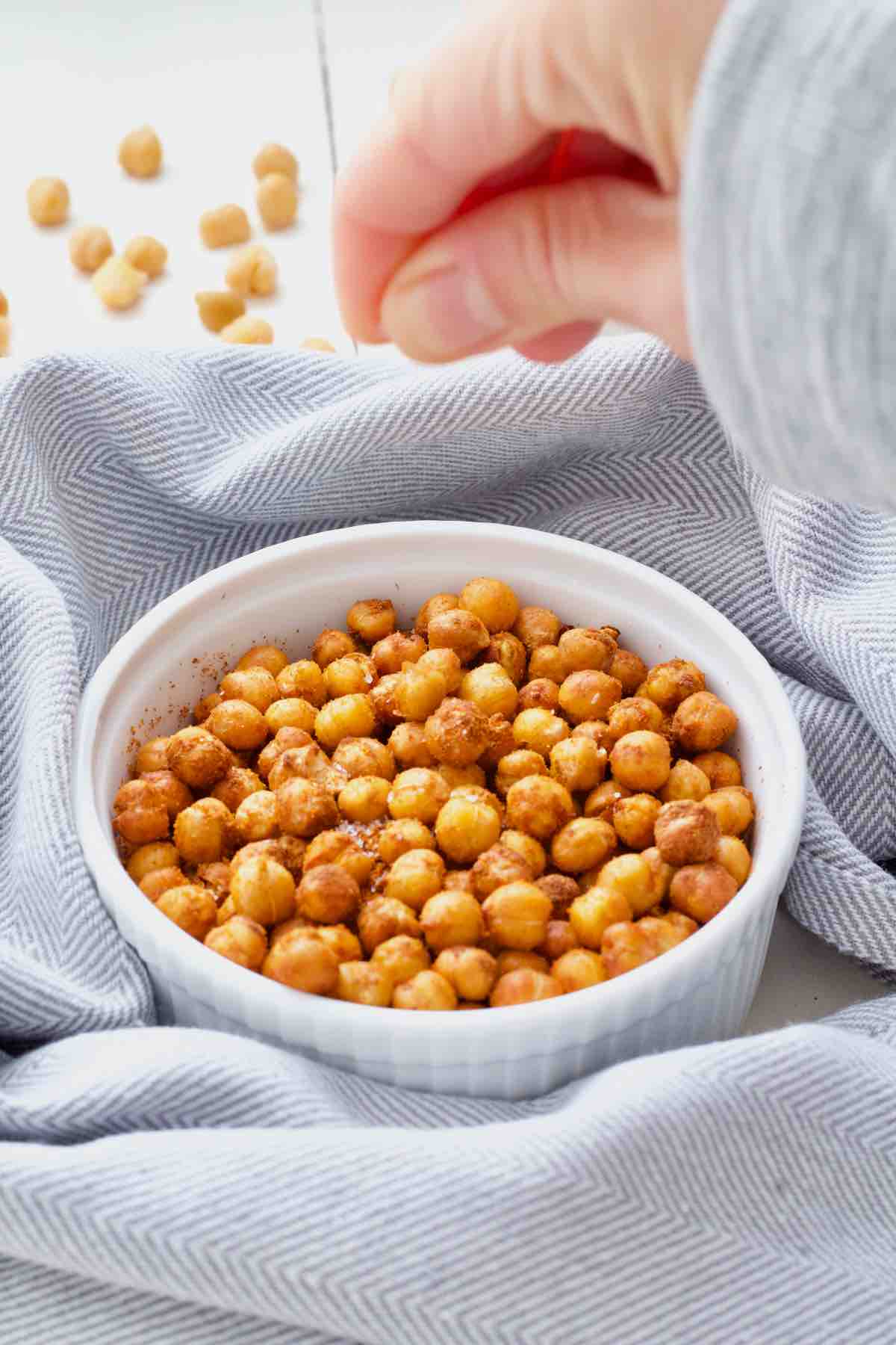 Hand sprinkling salt over chickpeas.