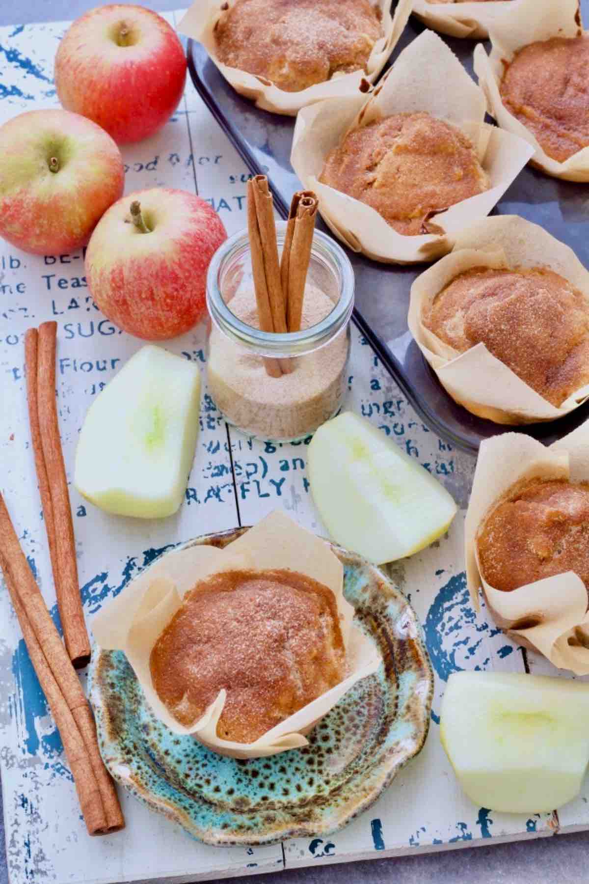 Apple and cinnamon muffins amongst apples and cinnamon sticks.