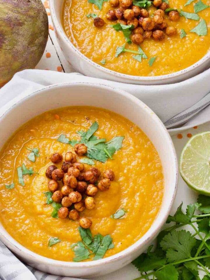 Carrot and swede soup in a bowl, half a lime and fresh coriander on the side.