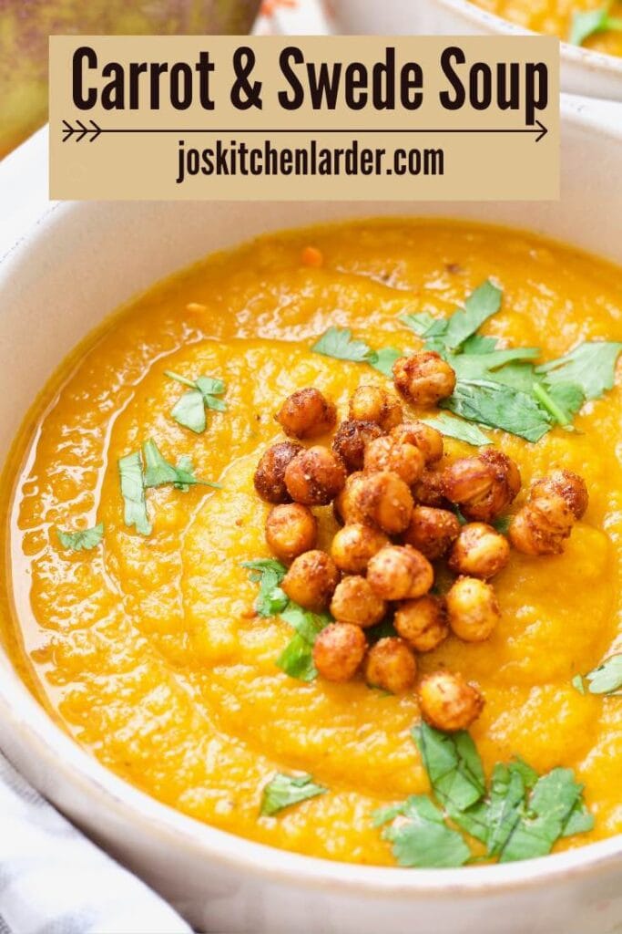 Close up of carrot and swede soup in a bowl garnished with chickpeas and coriander.