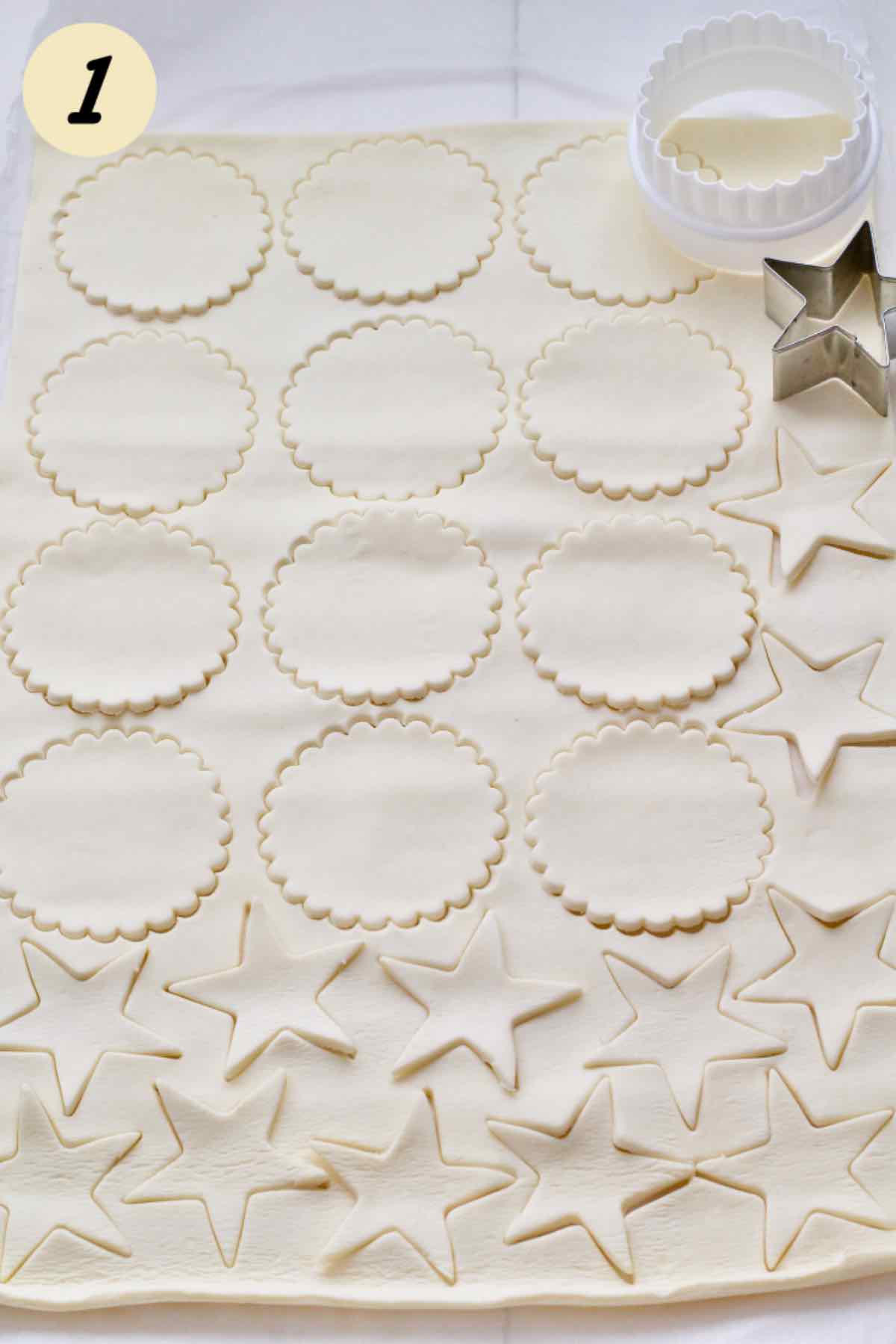Puff pastry sheet with fluted circles and stars cut out.