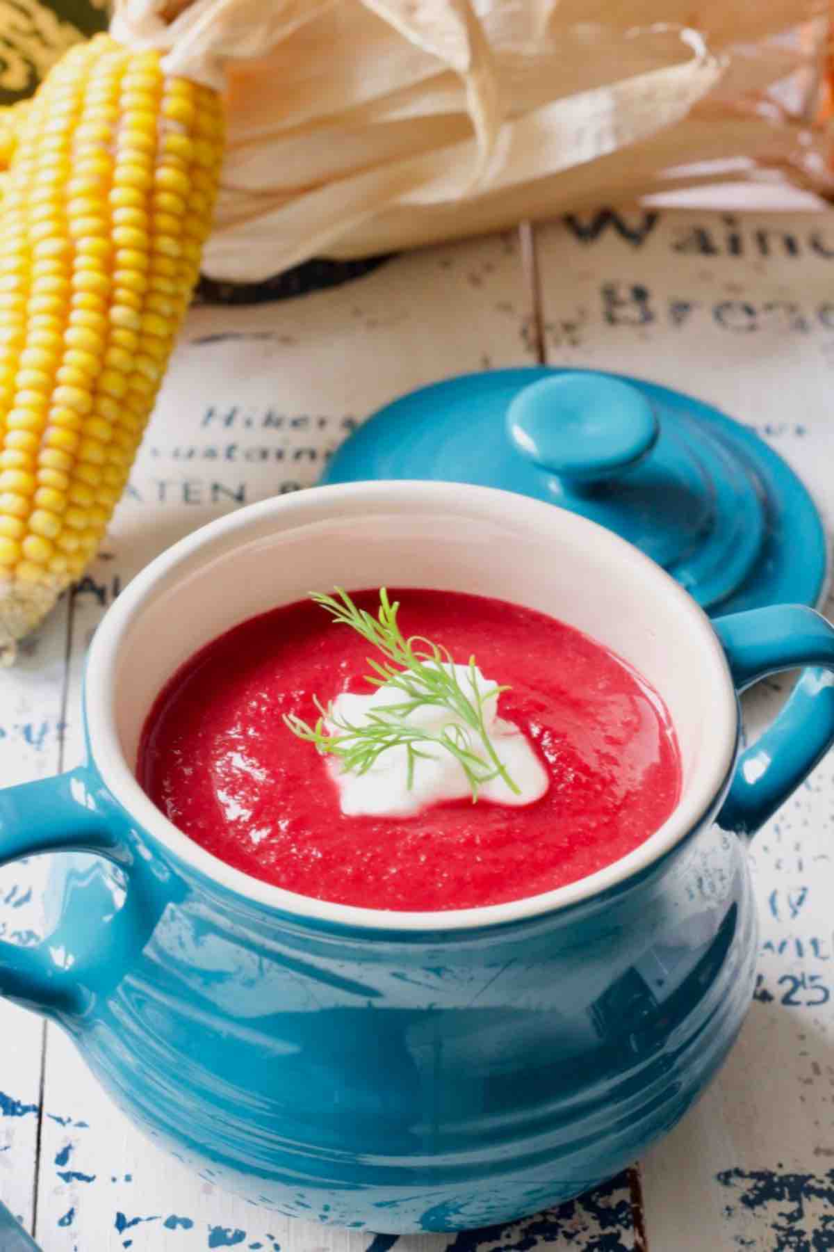 Beetroot soup in a soup bowl with yogurt and dill on top.