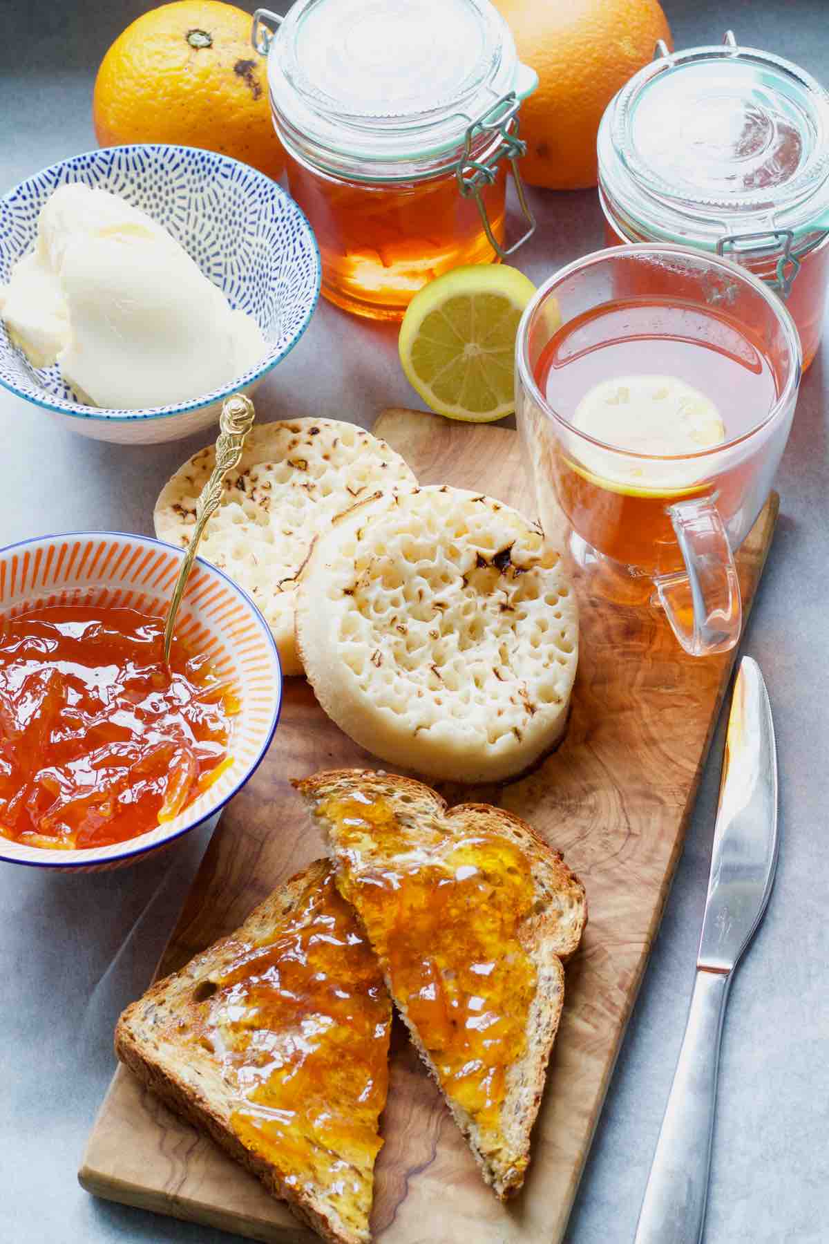 Breakfast set up with tea, toast, crumpets, butter and marmalade.