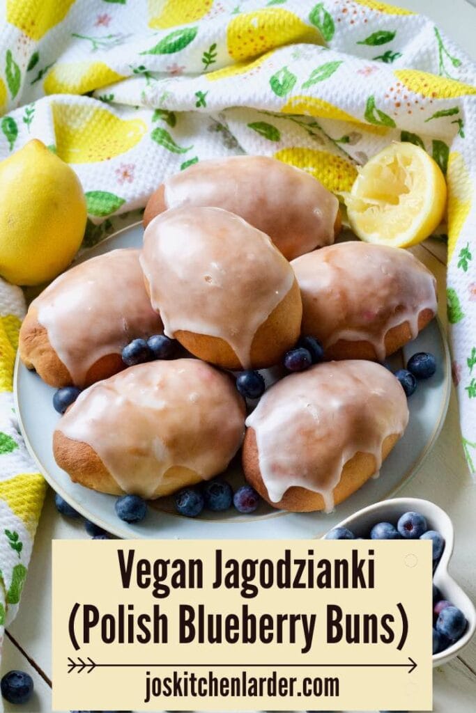 Glazed jagodzianki on a plate with blueberries around.