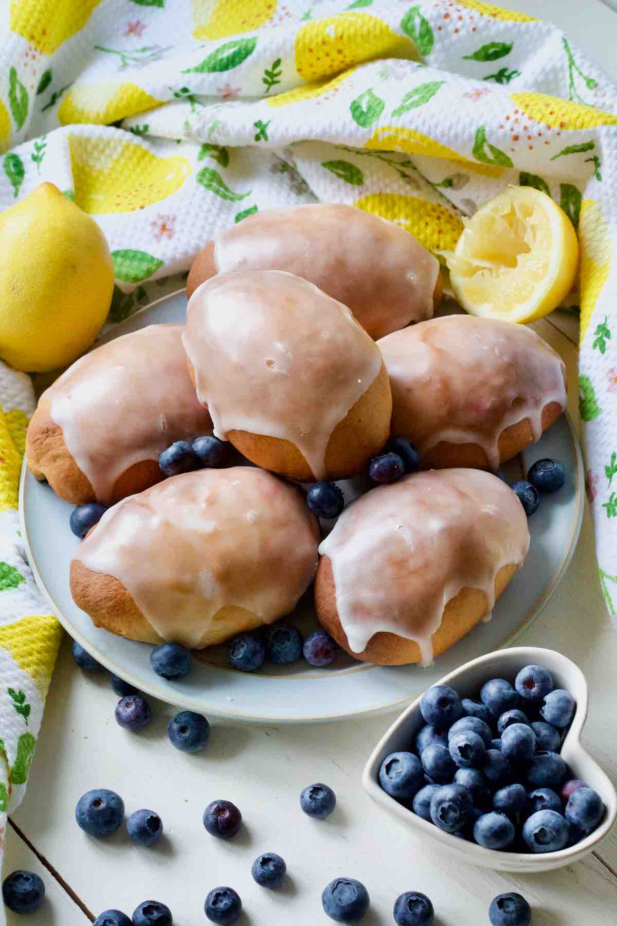 Glazed jagodzianki on a plate with blueberries around.