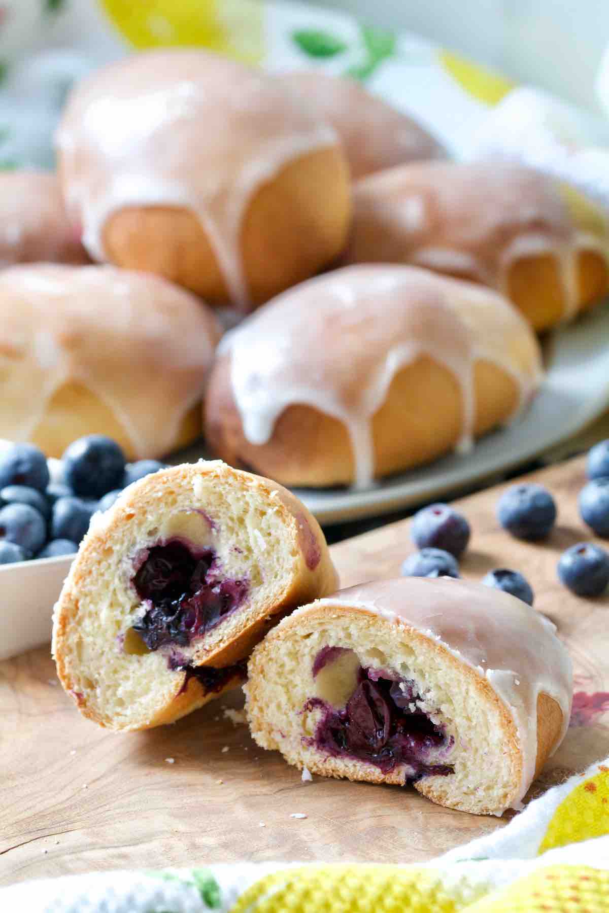 Blueberry bun cut in half with whole buns behind.