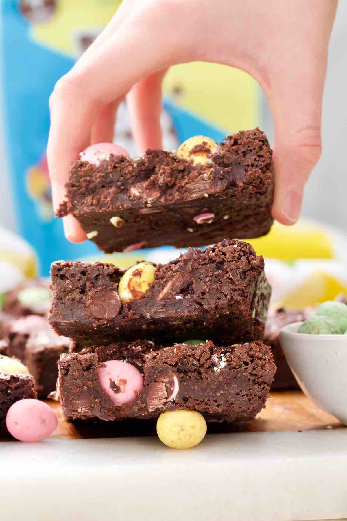 Hand lifting brownie from the stack.