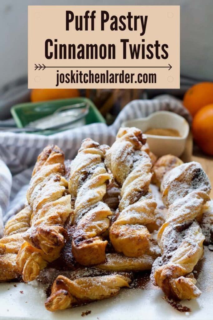 Pile of cinnamon twists dusted with icing sugar.