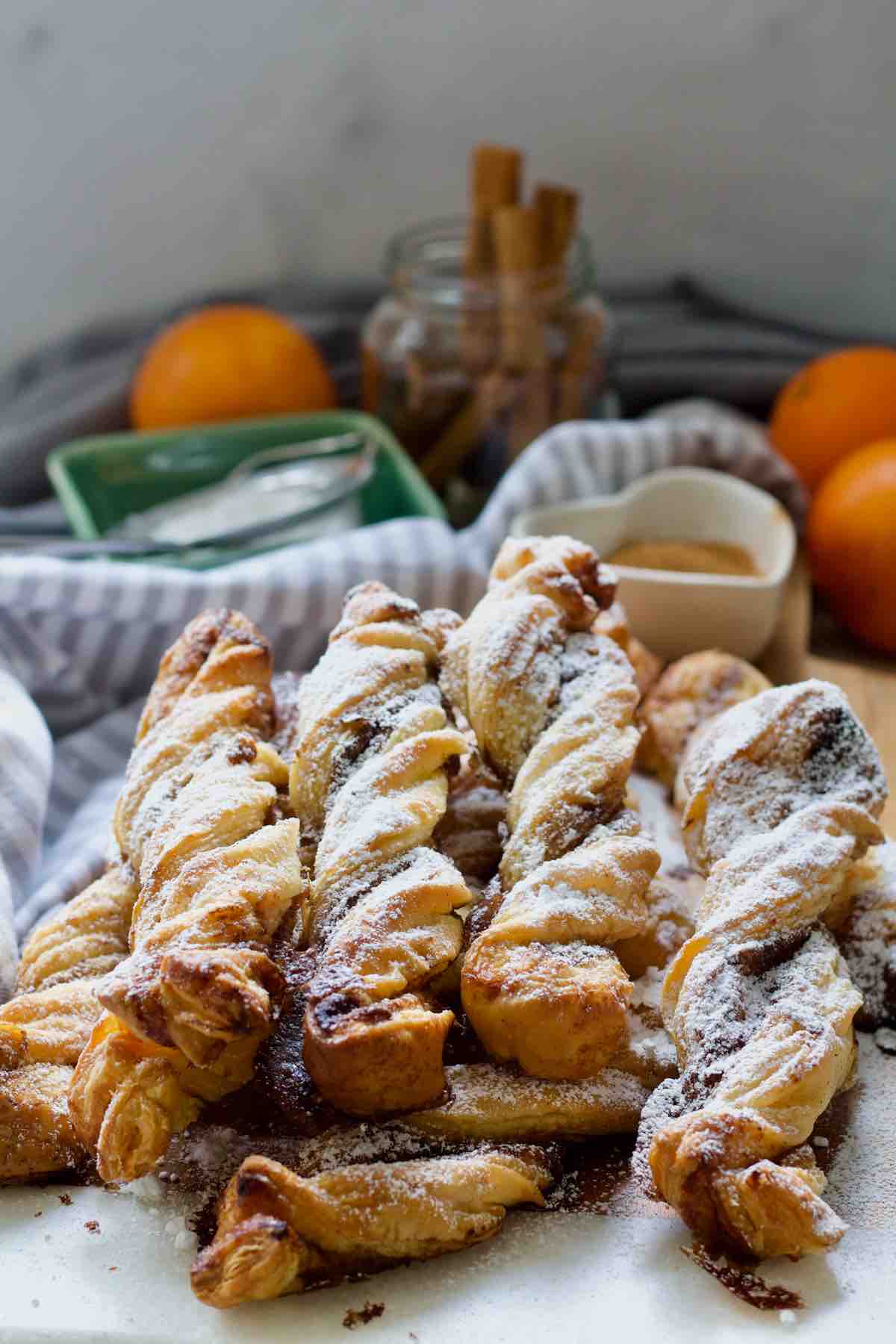 Pile of cinnamon twists dusted with icing sugar.