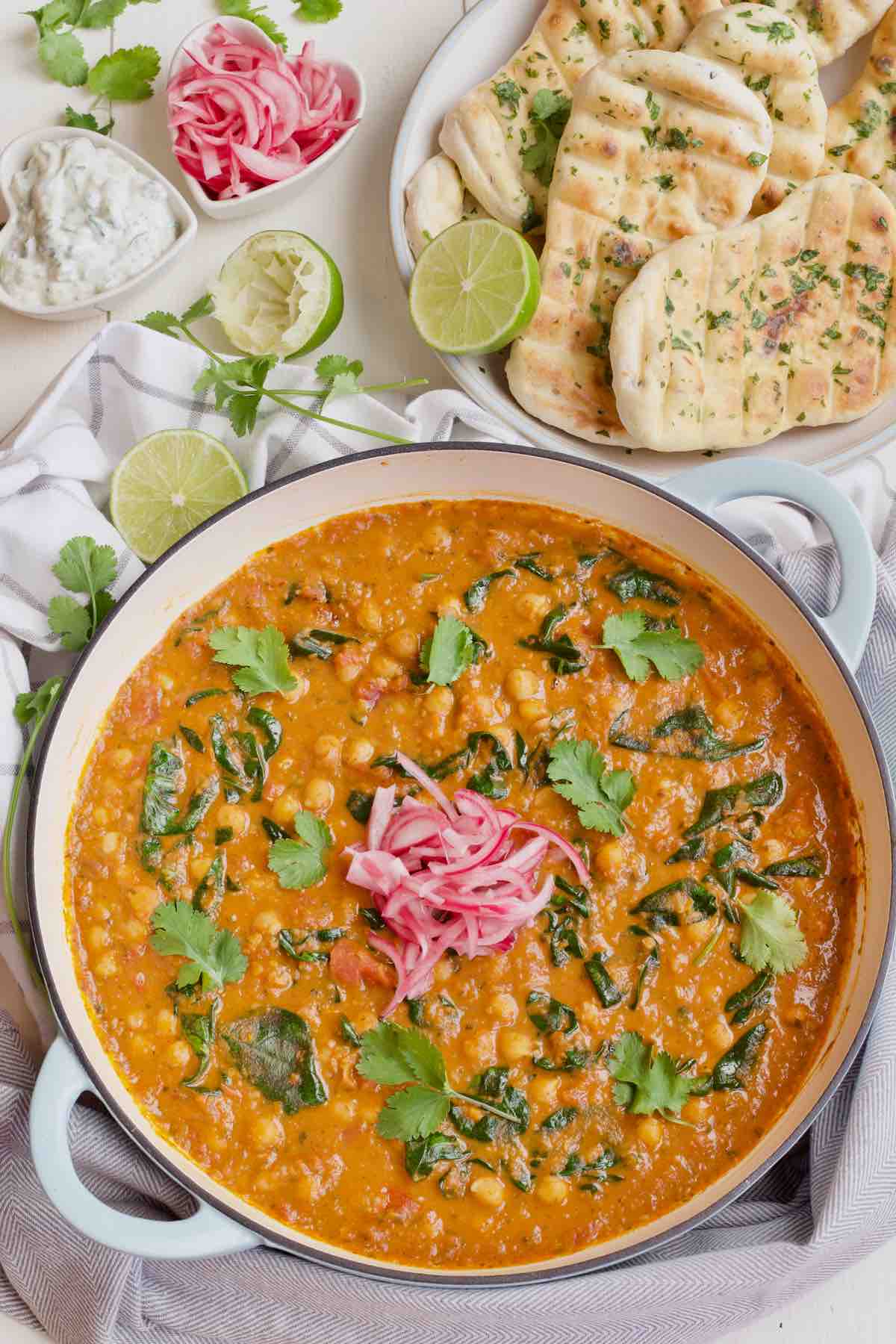 Pan with finished curry, condiments & naan breads.