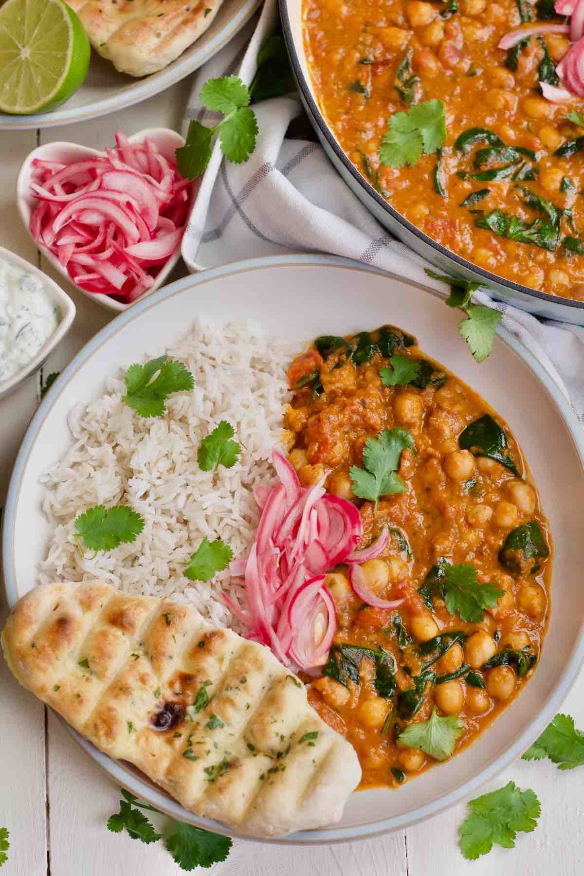 Bowl with curry, rice, naan bread and pickled onions.
