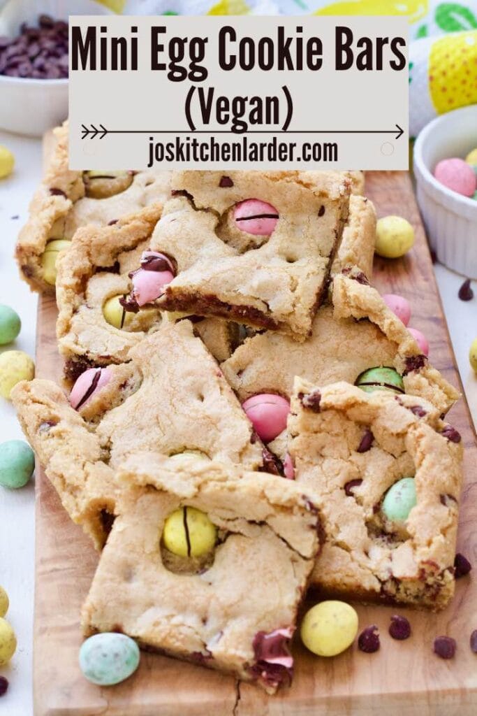 Mini egg cookie bar squares piled up on a board.