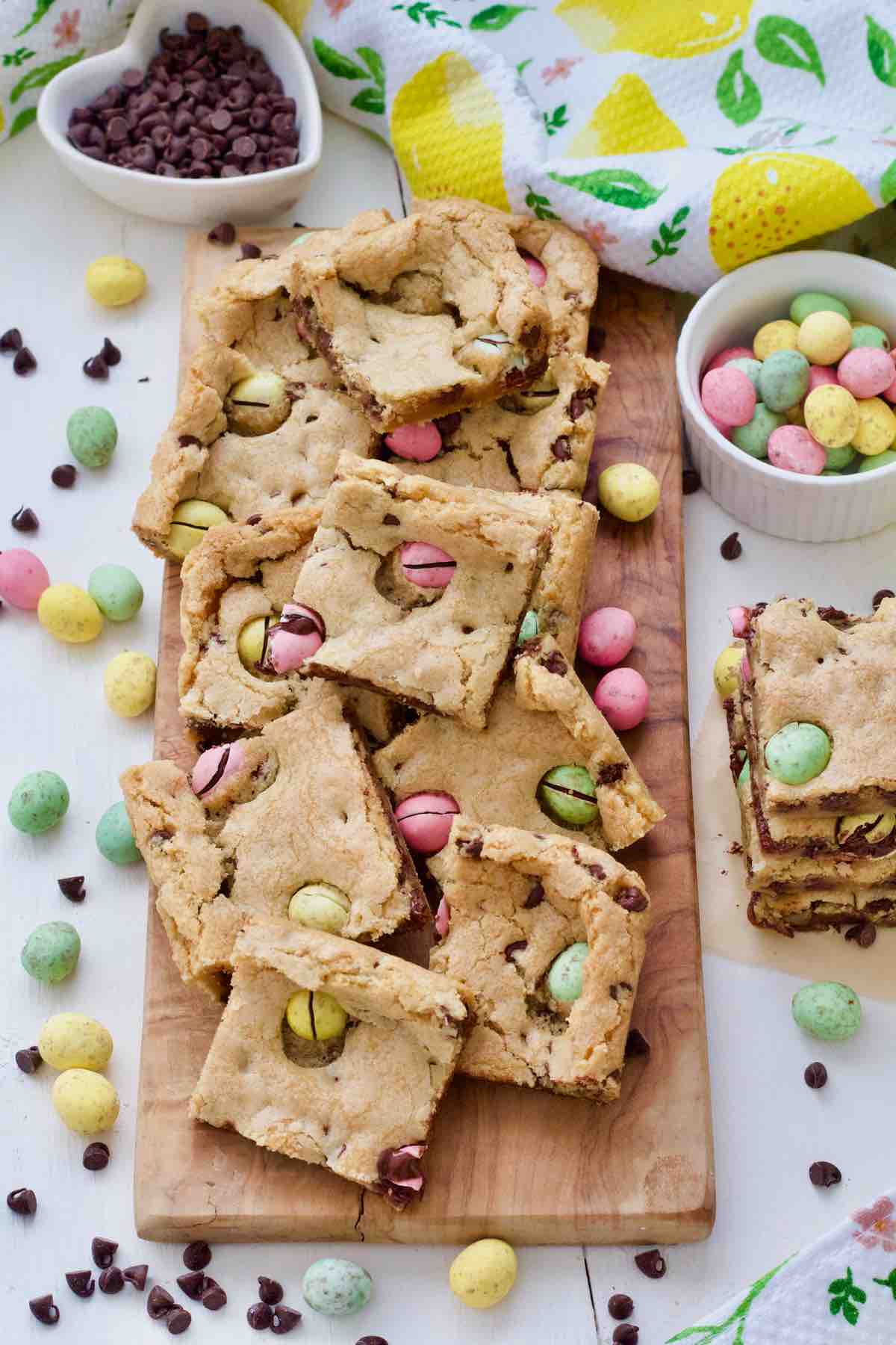 Cookie bars on a board with extra mini eggs and chocolate chips.