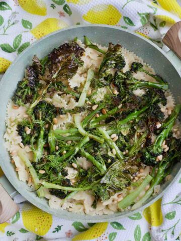 Pan full of hummus pasta, purple sprouting broccoli, pine nuts and dill.