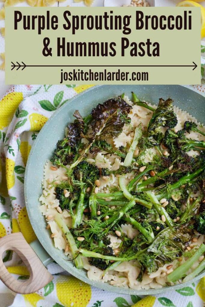 Pan with hummus pasta topped with purple sprouting broccoli.