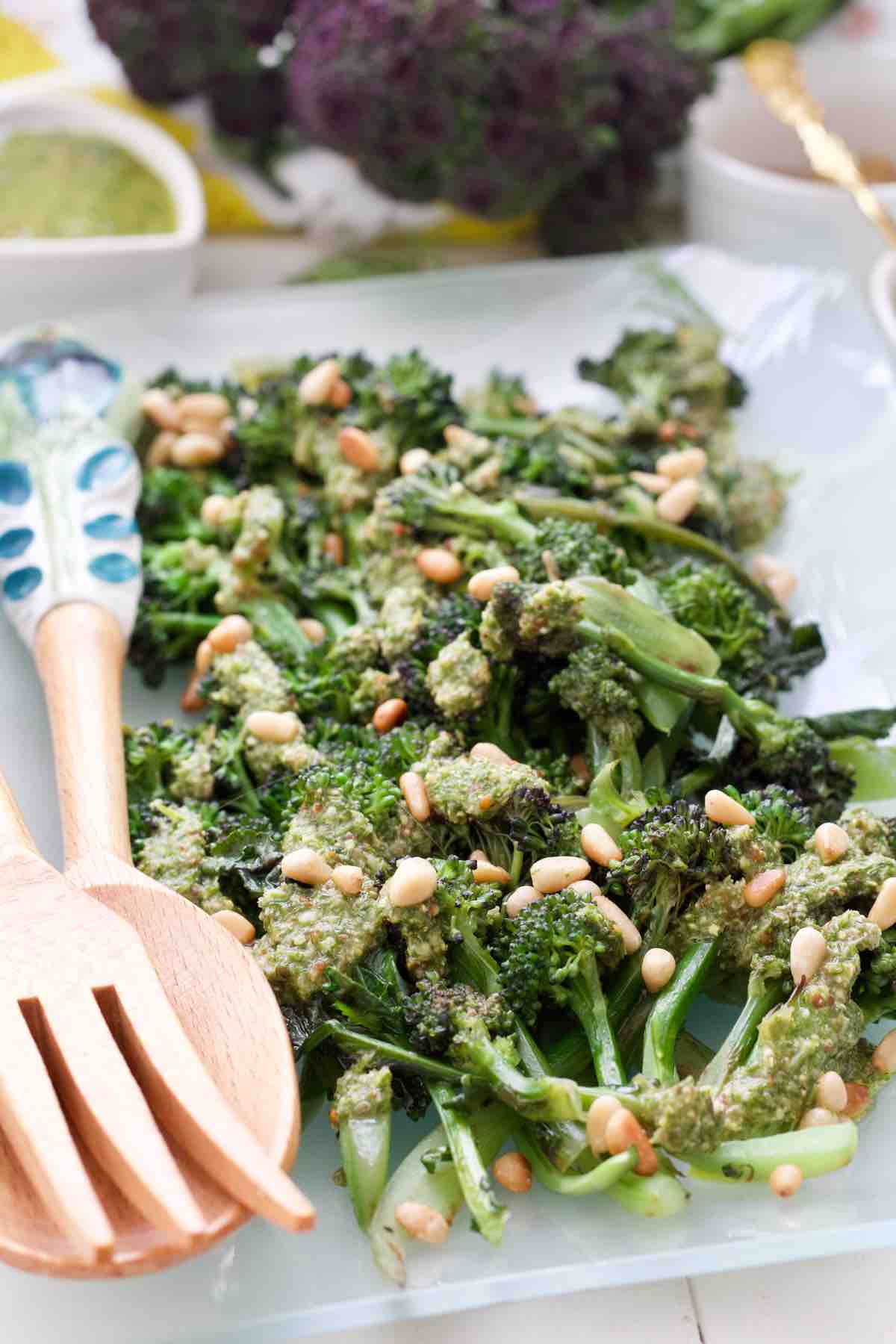 Purple sprouting broccoli with green salsa, serving spoons.