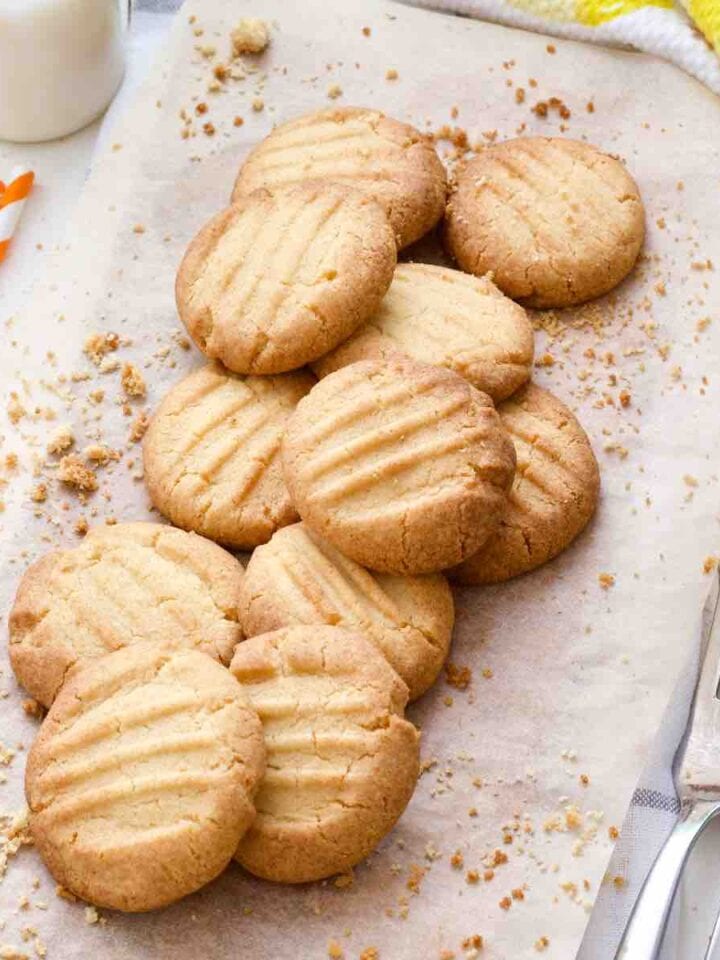 Close up of baked fork biscuits on a baking paper with crumbs around.