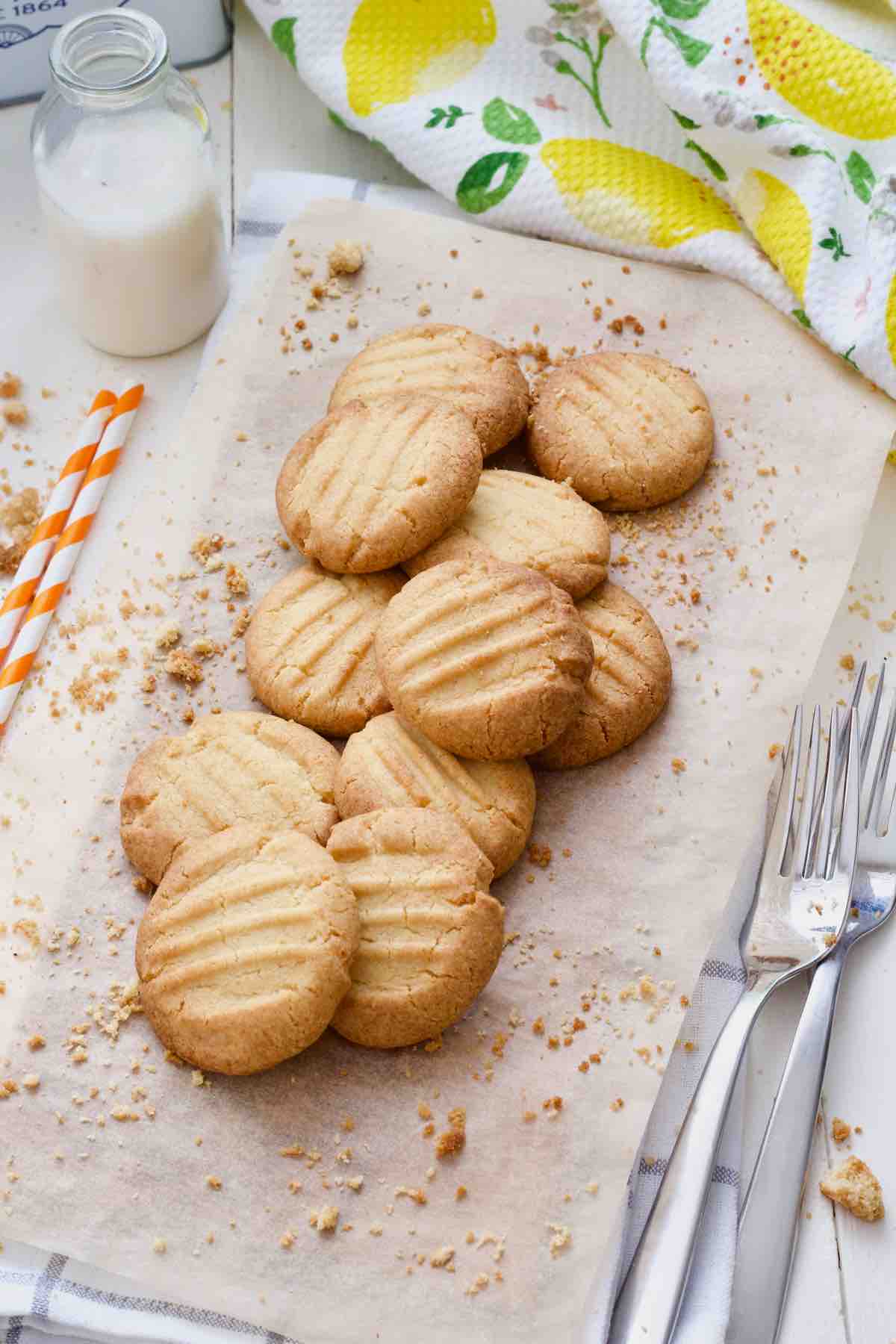 Bird view of fork biscuits on a piece of baking paper with crumbs around.