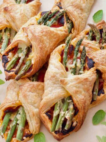 Square image showing baked asparagus puff pastry parcels.