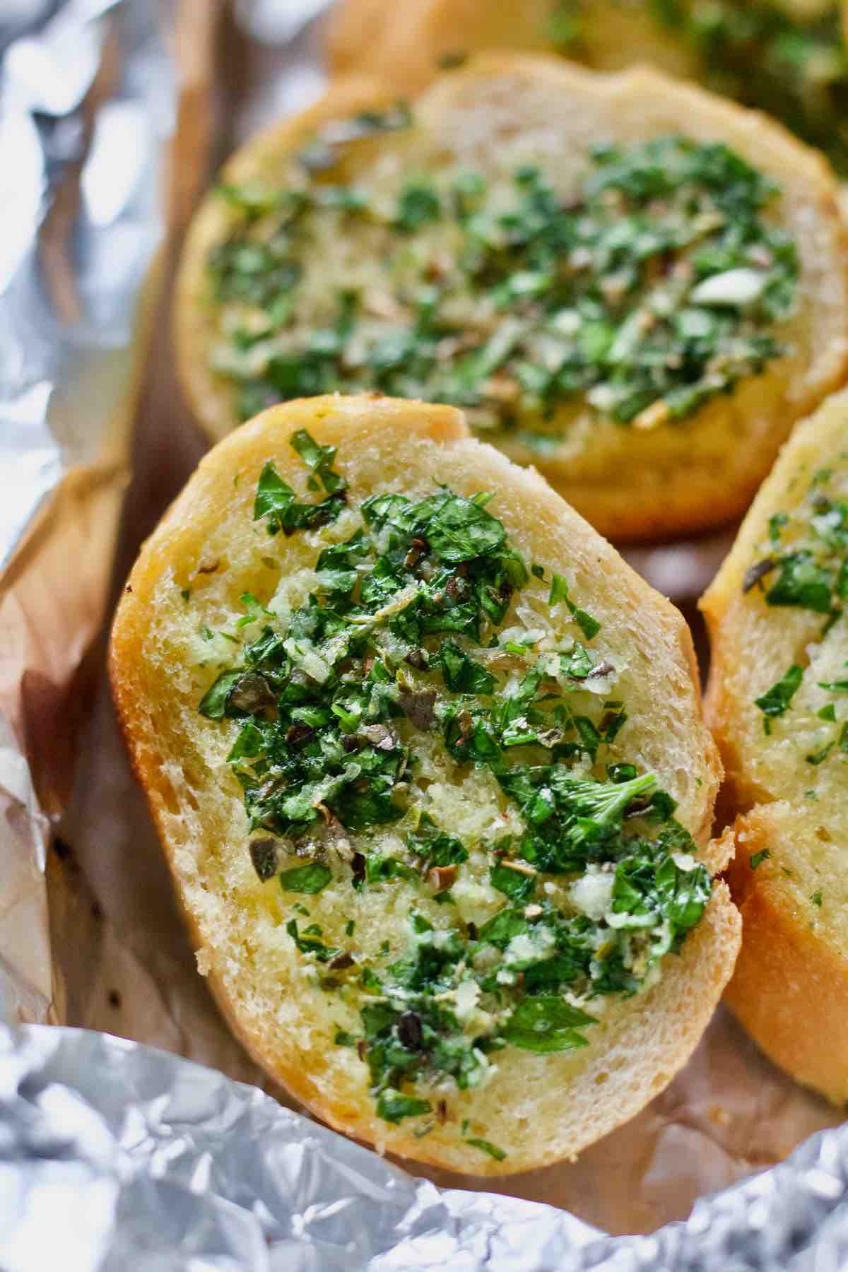 Close up of a slice of baked vegan garlic bread with garlic parsley butter.