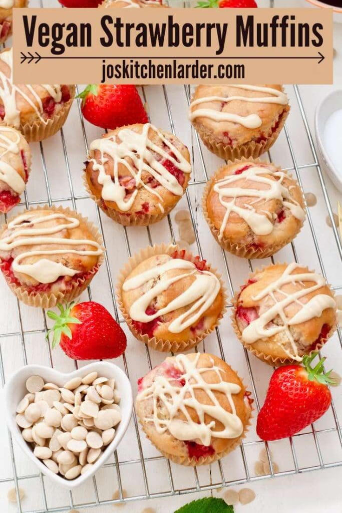 Vegan strawberry muffins with white chocolate drizzle on a cooling rack.