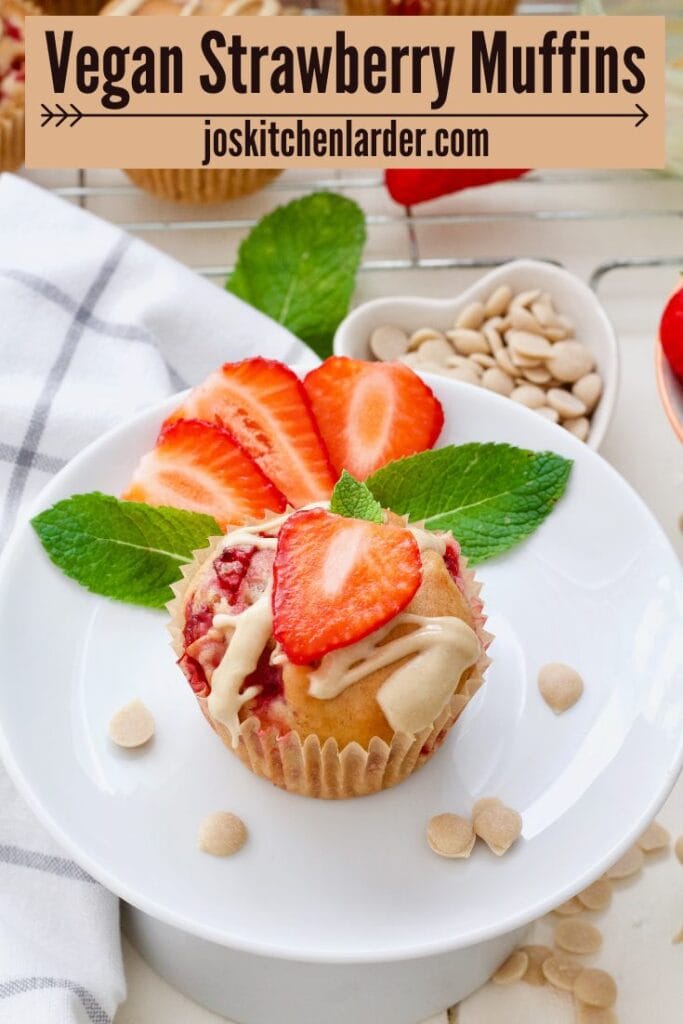 Strawberry muffin on a plate decorated with a slice of strawberry and mint leaves.