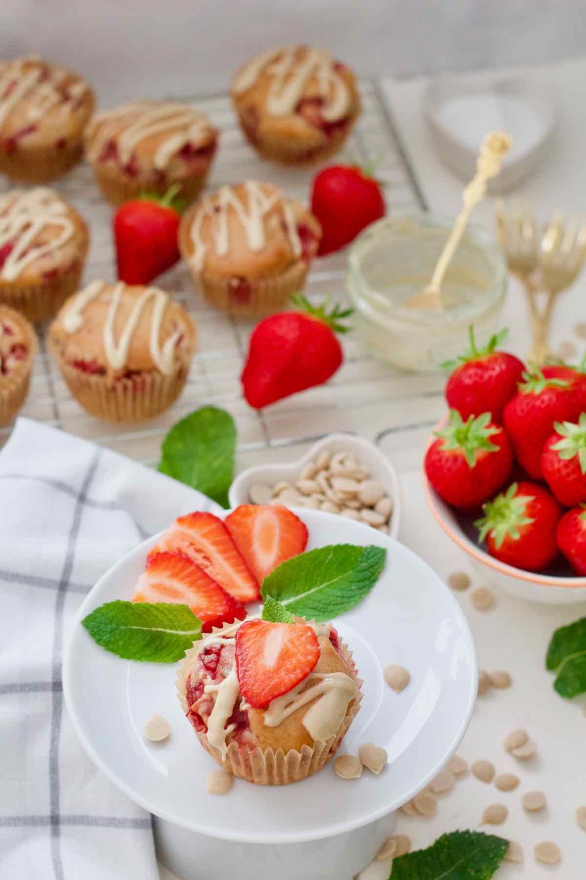 Decorated vegan strawberry muffin on a plate with more muffins in the background.