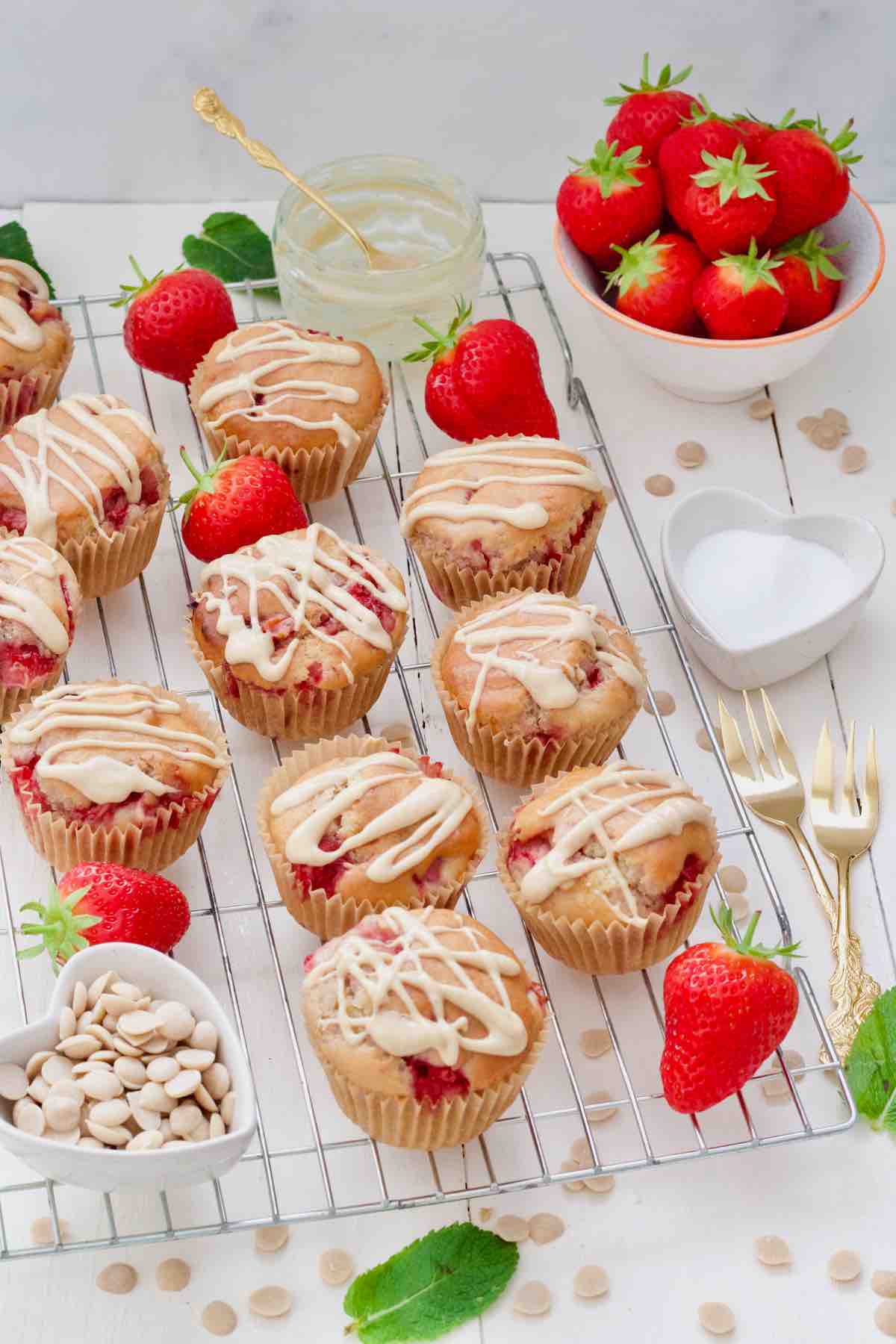 Strawberry muffins on a rack, fresh strawberries, mint leaves, white chocolate chips.