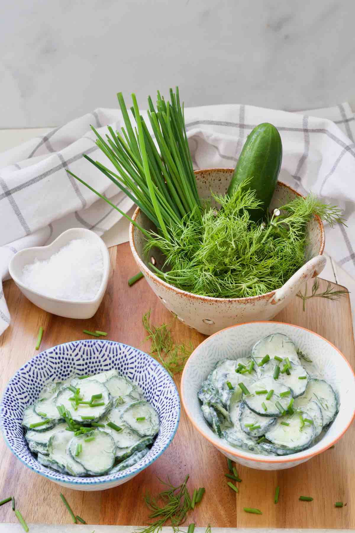 Two bowl with mizeria, dish with sea salt and colander with herb & cucumber.