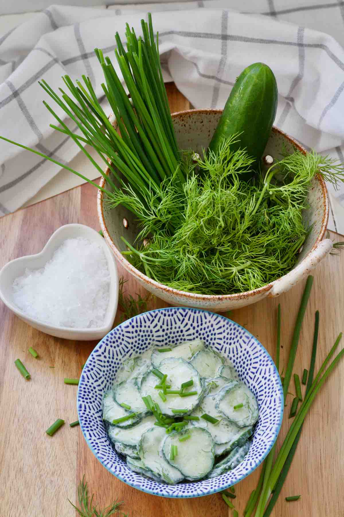 Mizeria, dish with sea salt and colander with herbs and cucumber.