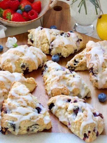 Vegan blueberry scones on a board with blueberries scattered around.