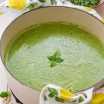 Close up of pot with courgette soup with peas and mint.