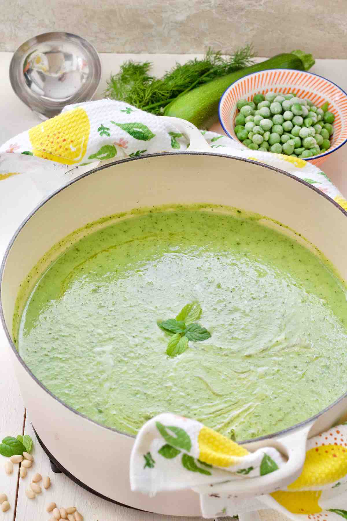 Pot with courgette soup with peas and mint.