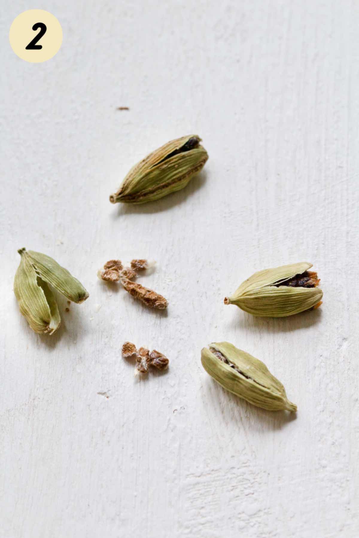 Cardamom pods split slightly with some seeds out.