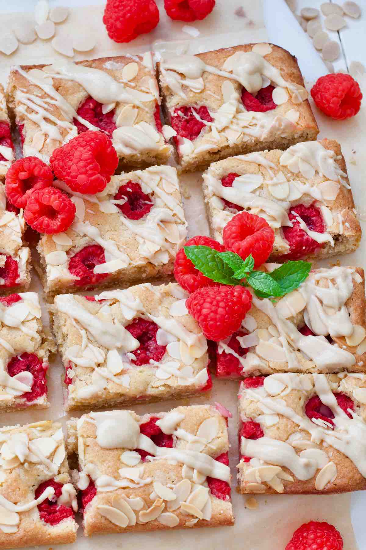 8 raspberry blondies decorated with fresh raspberries and some mint.