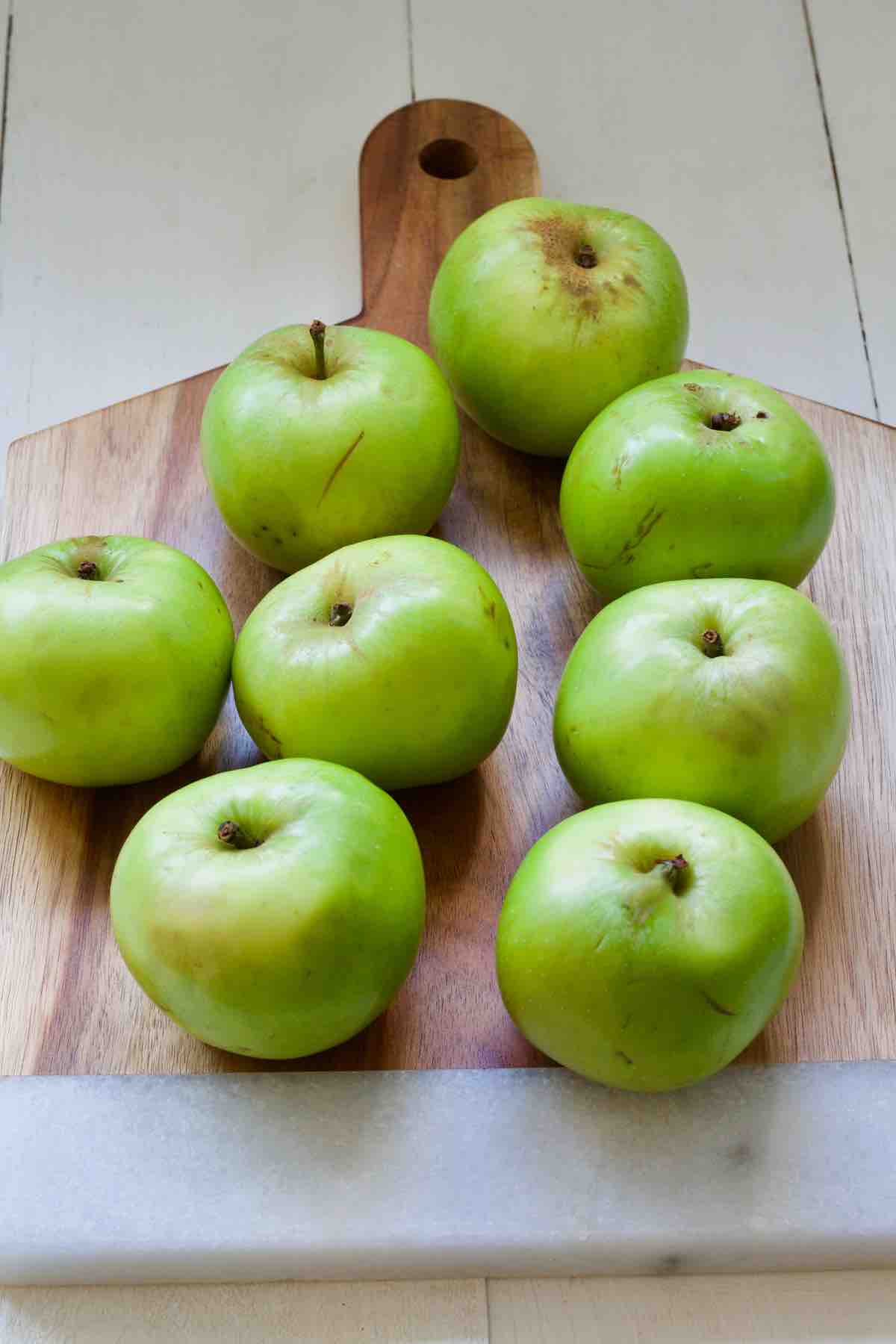 Green cooking apples on a cutting board.