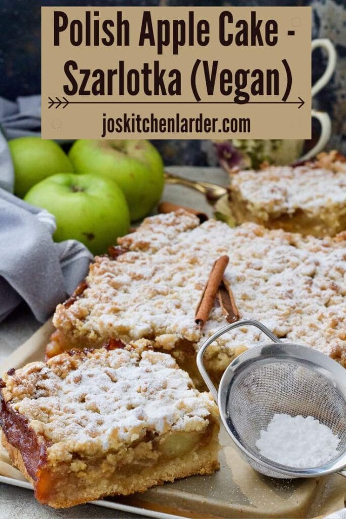 Polish apple cake with a slice cut and a small sieve with icing sugar.