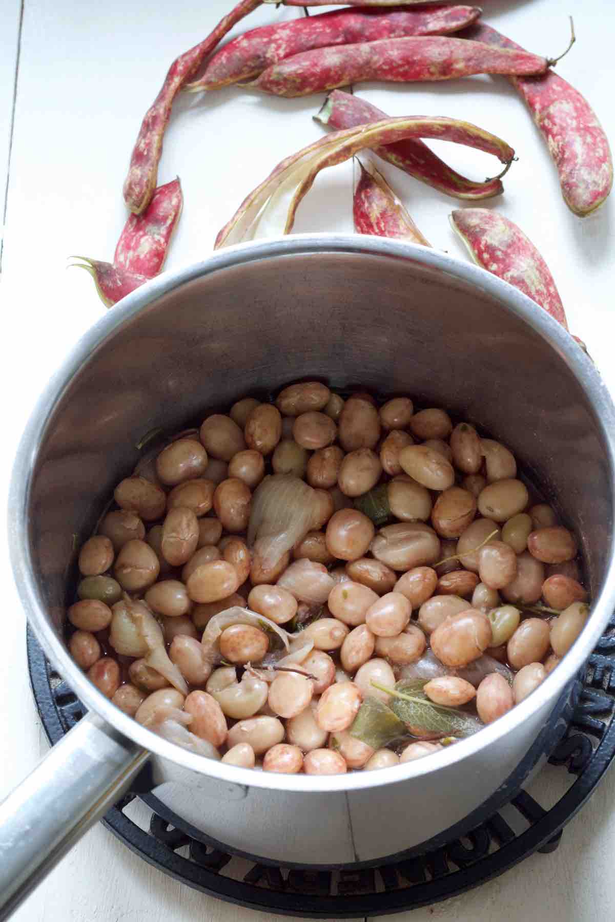 Borlotti beans in a pan with aromatics after cooking has finished.
