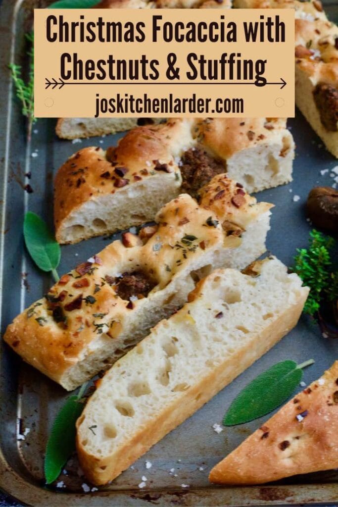 Focaccia slices on a baking sheet with some fresh herbs.