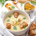 Close up of curried parsnip soup in a bowl with garnishes.