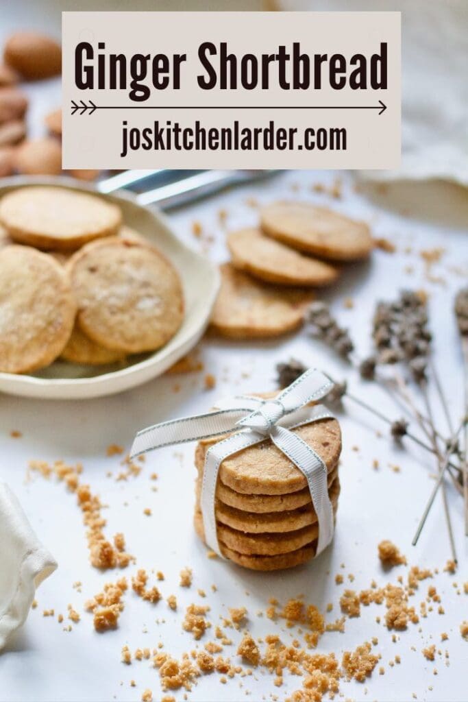 Stack of ginger shortbread with crumbs around and more shortbread behind.