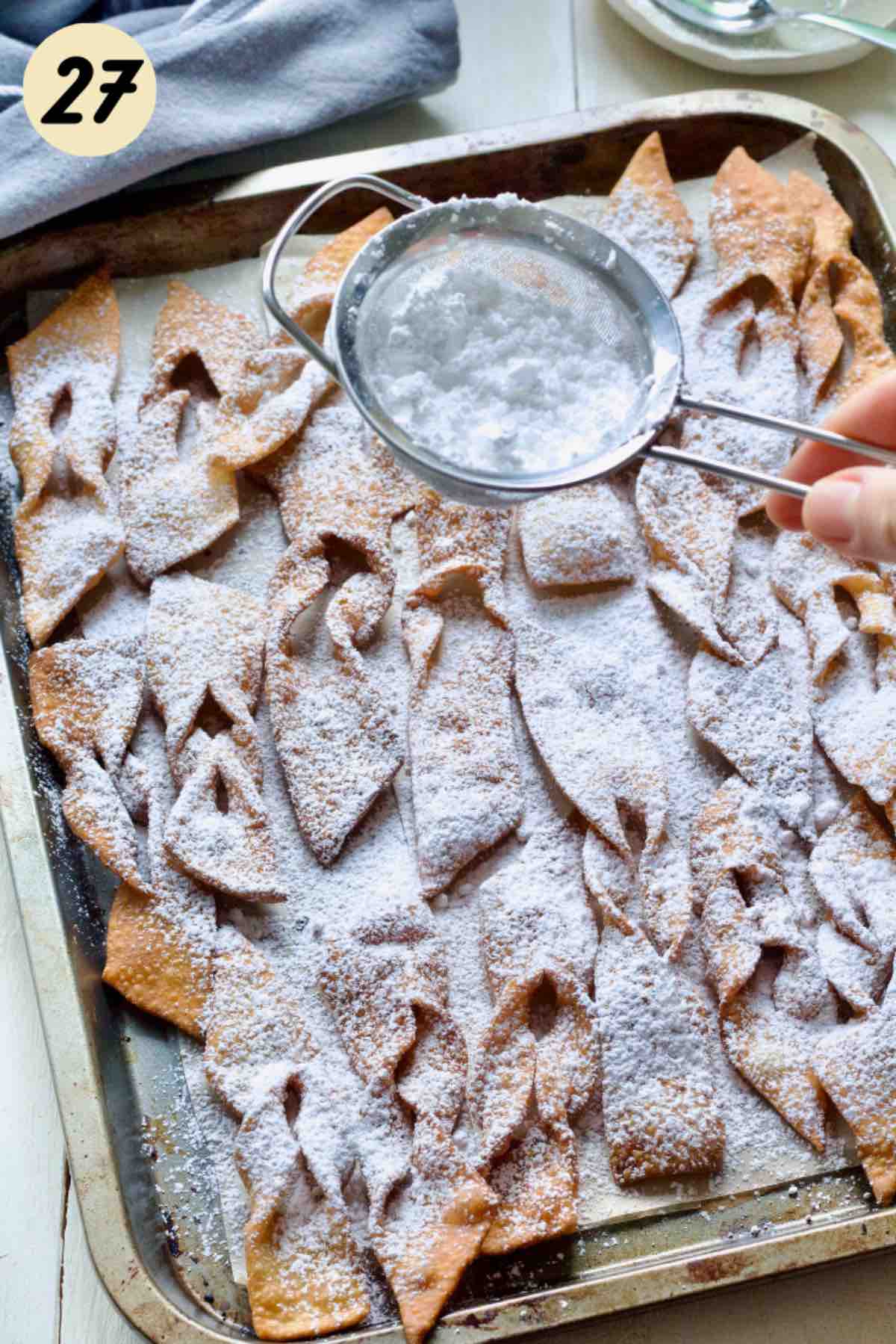 Faworki being dusted with icing sugar.