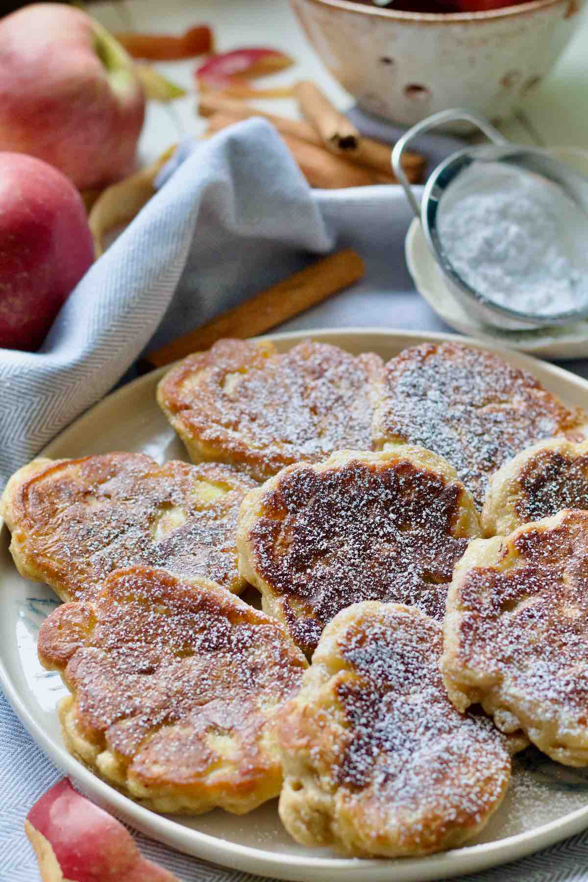 Close up of icing sugar dusted apple pancakes on a plate.