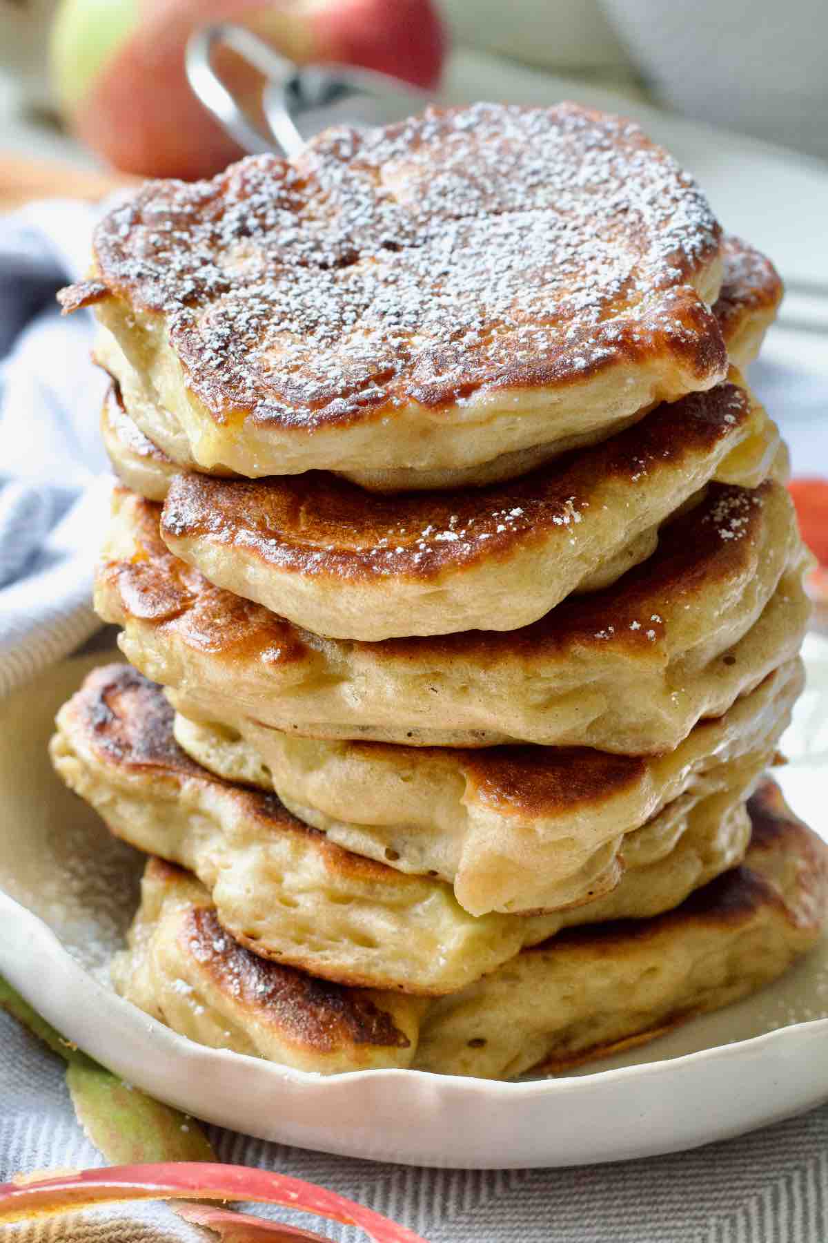 Stack of pancakes on a plate, top one dusted with icing sugar.