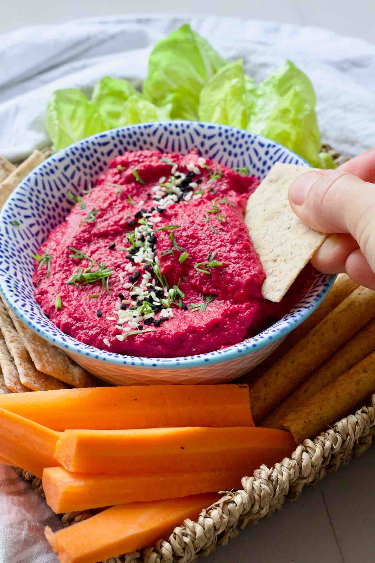 Scooping hummus onto a cracker.