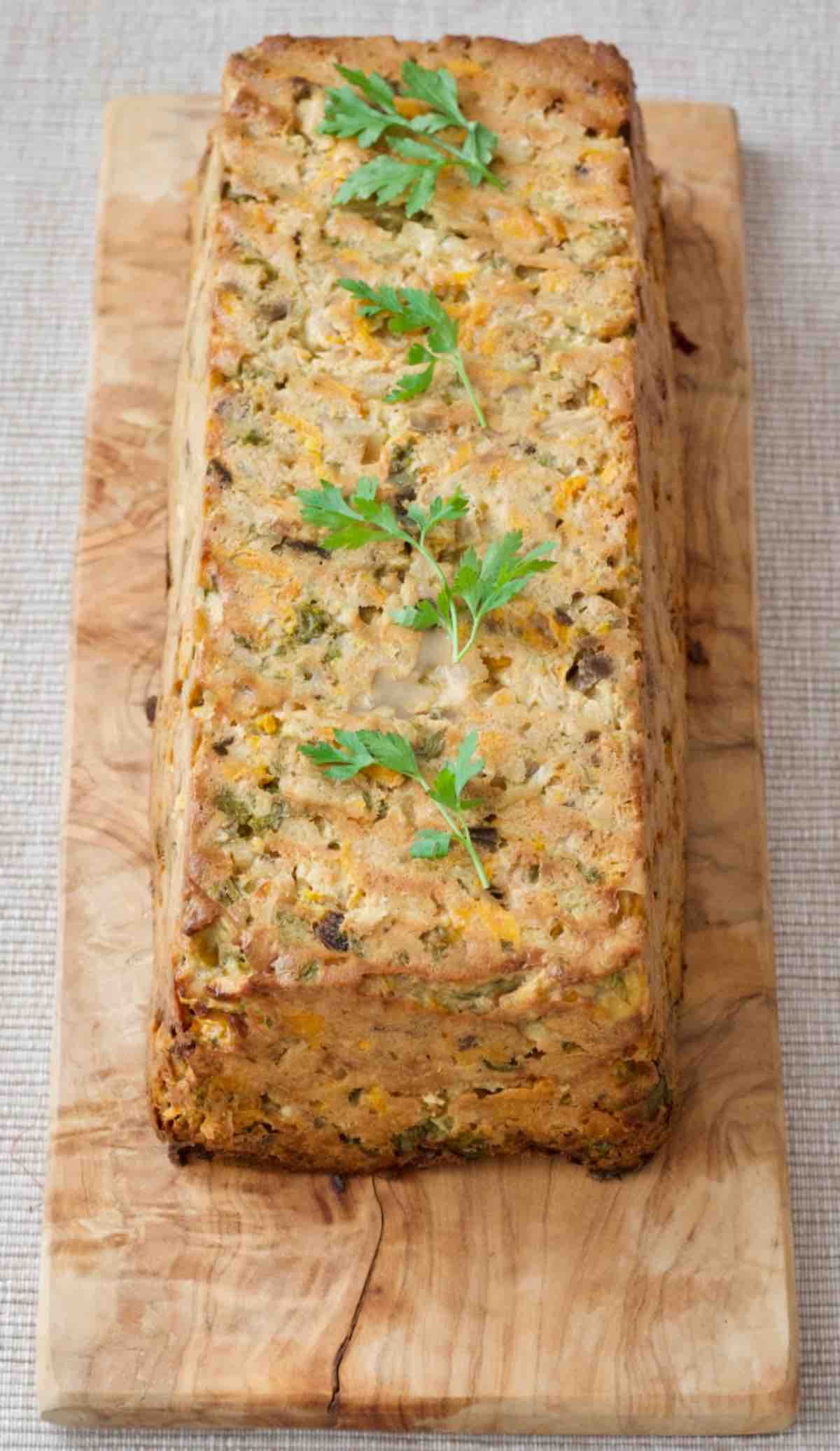 Celeriac veggie loaf presented simply on a board garnished with parsley.