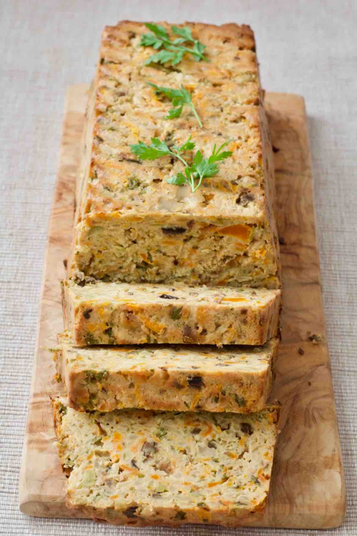 Celeriac veggie loaf on a board with three slices cut to show the inside.