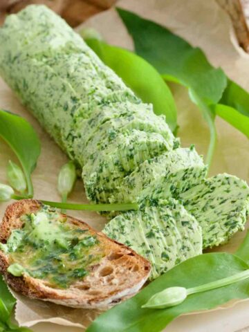 Wild garlic butter on toast with the log of butter and garlic leaves.