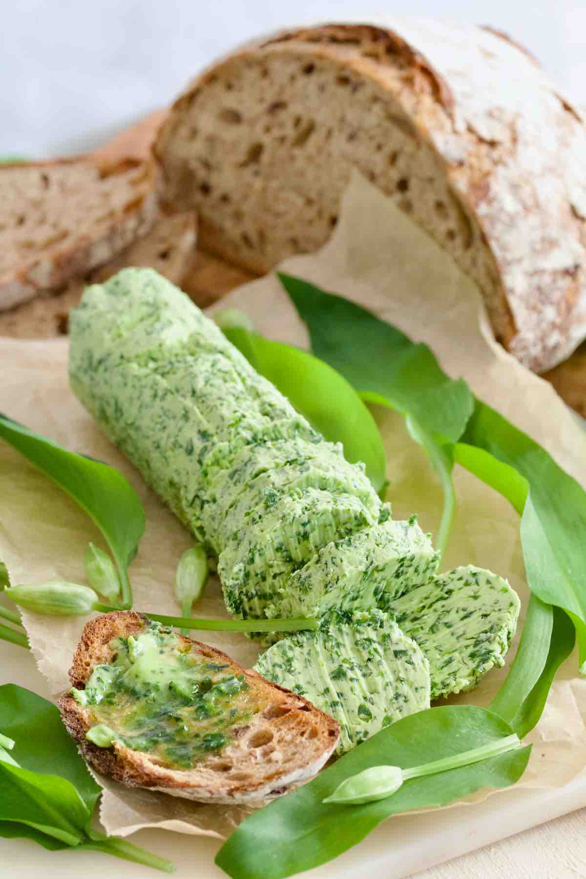 Log of wild garlic butter with cut slices and sourdough toast with melting butter.
