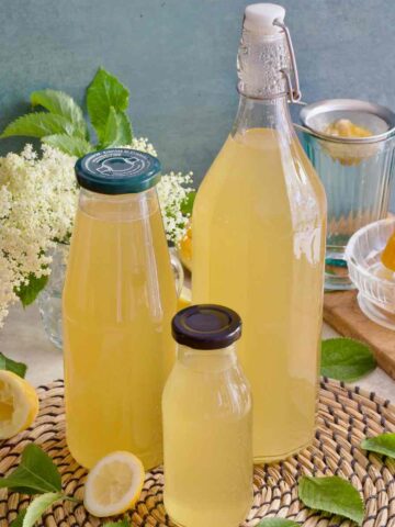 Close up of three bottles filled with elderflower cordial.